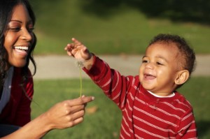 Mother and son playing with a dandelion in the park